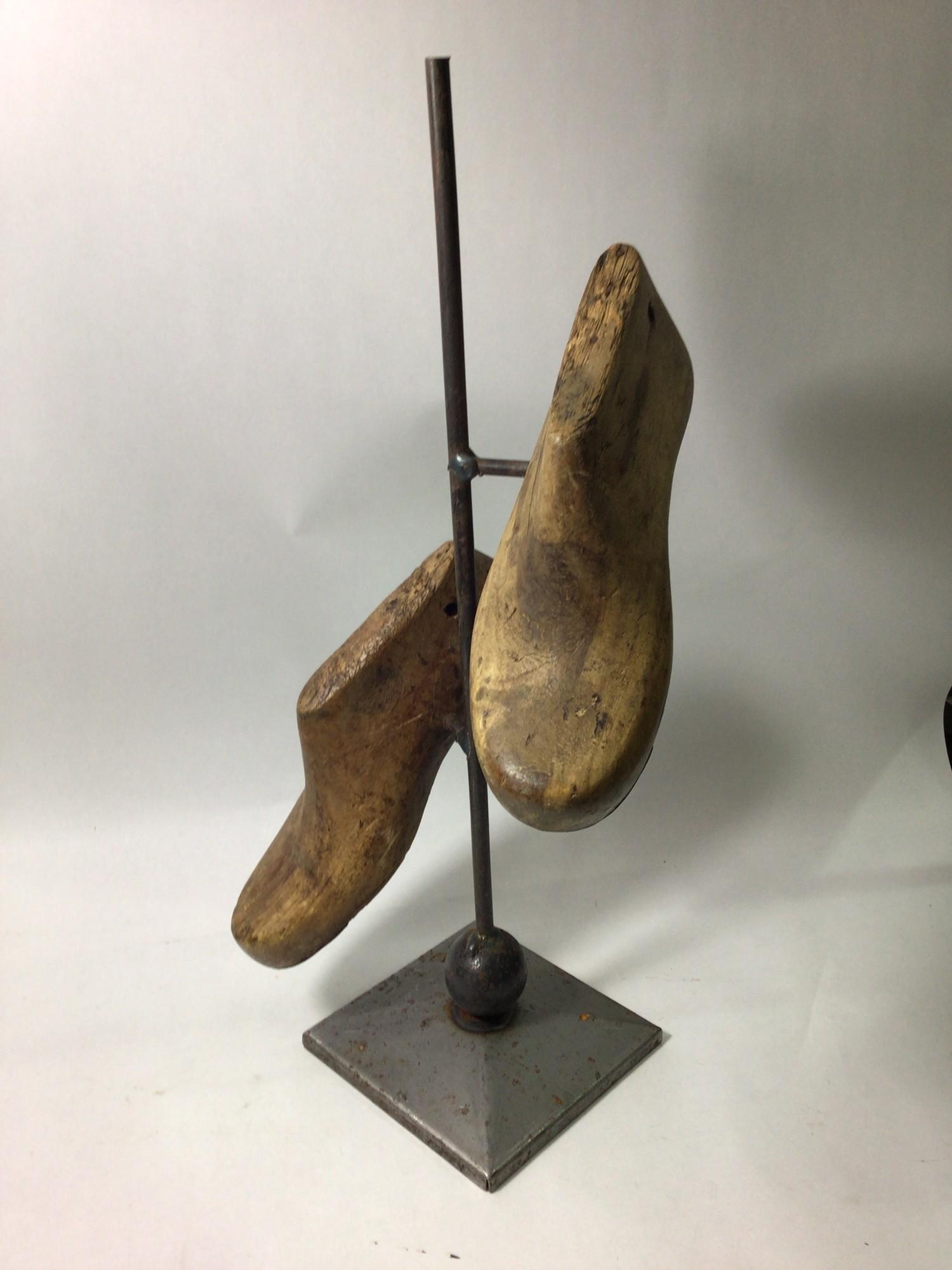 A modern sculpture of two antique cobbler's wooden shoe inserts suspended on a vertical metal - Bild 2 aus 2