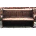 A wooden church pew with panelled back and shaped end supports, 162cm wide