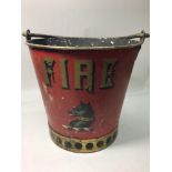 A red painted metal fire bucket with gold lettering and a painted motif of a black wolf with gold