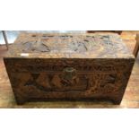 An Oriental heavily carved camphor lined blanket chest, carved with scenes of sailing boats,