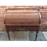 An early 20th century oak roll-top desk, enclosed pigeonholes and sliding triple writing scribe with