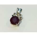 An 18ct white gold pendant set with a large Ruby, measuring 13mm, and a small round diamond to the