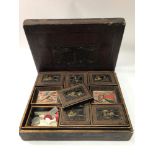 A Japanese black lacquered games box decorated with scenes of houses amidst trees, the cover