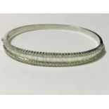 A ladies 18ct white gold triple diamond set bangle. To the centre is set a graduated row of
