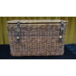 An oversized wicker basket/hamper of rectangular form, with leather strap locks and handle to either