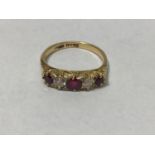 An 18ct gold five stone ring, with carved mount, claw set with three graduated rubies and two