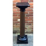 An ebonised wooden pedestal, the top of square section, raised on a turned and fluted column to