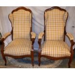 A near pair of French provincial fruitwood voltaires, the upholstered semi winged backs with the