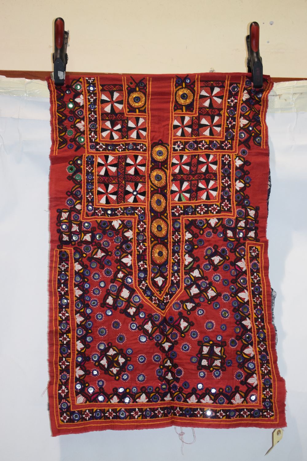 Two Indian textiles, Kutch, west India, the first a red cotton dress front, embroidered with flowers