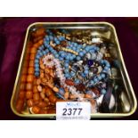 A tin of mixed jewellery, beads etc.