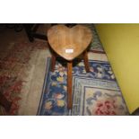 A primitive Arts and Crafts type stool having three splayed chamfered legs the top in the shape of
