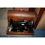 A wooden cased, hand wheel vintage Singer sewing machine, key present.