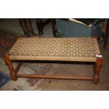 A woven seated double Stool having turned oak legs with perimeter stretchers,