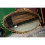 An oval bevel plate mirror with gilt surround.