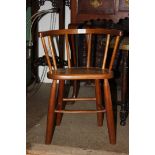 A solid wood seated child's Bow back Armchair having turned legs,