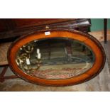 An oak framed bevelled oval wall mirror, 33" x 21 1/2".