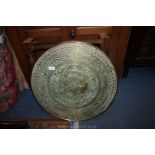 An Eastern brass topped circular Table, the folding base having turned legs, 23 1/2'' diameter,