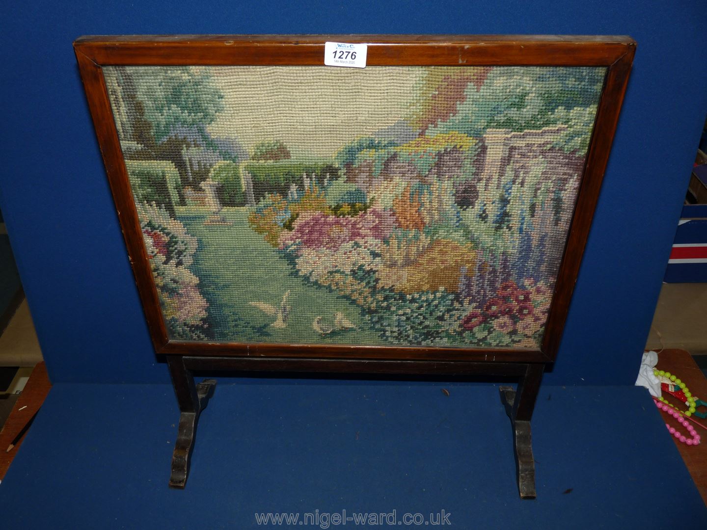 A small wooden Firescreen having tapestry of birds in a garden.