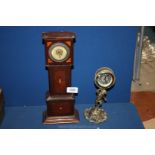 A small wooden Mantle clock in the shape of a Grandfather clock plus one other.