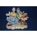 A large Capo di Monte style ornament of a tramp and an elderly lady sitting on a bench.