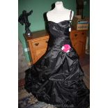 A black ball gown with pink sequin detail to the bodice and a pink and white rose on the hip of