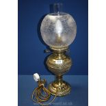A brass oil Lamp converted to electric with decorated panels around the base and lamp,