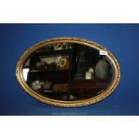 An oval gilt framed mirror by Clark Eaton, December 1979. 24" x 15". Good condition.