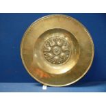 An antique Nuremberg brass alms dish typically decorated with a band of flowers around a central