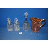A pair of small square decanters, a larger pressed glass decanter and a heavy vaseline glass jug,