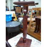 A dark Mahogany plant stand/lamp table with brass feet.