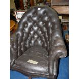 A leather swivel button-back library armchair.