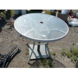 A glass top table with metal base for parasol.