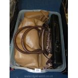 A box of tan coloured handbags and a black faux leather brief case.