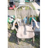 A wooden wheel-back elbow chair for repair.