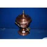 A copper hot water urn with brass tap and handles.