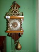 A Wall Clock having Atlas pediment, chiming movement and pear shaped brass weights,