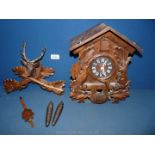 A Cuckoo clock with crossed rifles and stags head finial