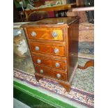 A compact reproduction Mahogany lightwood strung and crossbanded Chest of four short drawers,