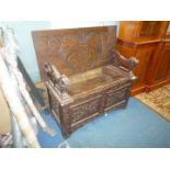 A carved decorated Oak Monks Seat having stylised foliage decorated panels to the base,