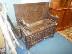 A carved decorated Oak Monks Seat having stylised foliage decorated panels to the base,