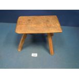 A primitive, country-made Stool having four rough-hewn socket-mounted legs.