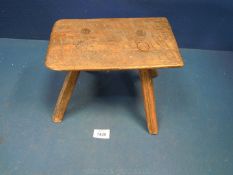 A primitive, country-made Stool having four rough-hewn socket-mounted legs.