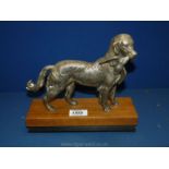 A metal model of a Retriever holding a Pheasant in its mouth on a plinth,