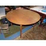 A 1960's Teak finished top circular Dining Table having a fold-out leaf concealed beneath the top
