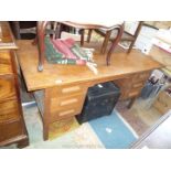 A mid Oak Kneehole Desk with three drawers to either side and raised on square legs,