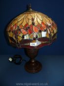 A large Tiffany style lamp with bronzed effect base and dragonfly to the rim, 22" tall.