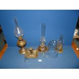 Three brass Oil Lamps with glass funnels, brass chamberstick and glass dome.