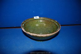 A speckled green glazed bowl by Ewenny Pottery; 1902, chips and wear to rim, 9 1/2" diameter,
