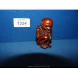 A Chinese carved wood figure of a crouched skeleton, 2 1/2'' tall.