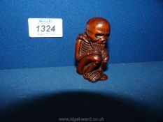 A Chinese carved wood figure of a crouched skeleton, 2 1/2'' tall.